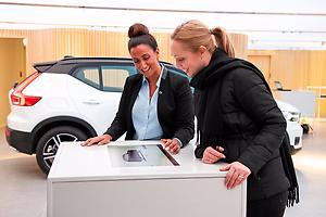 Två kvinnor kollar en skärm med försäljning av volvobilar